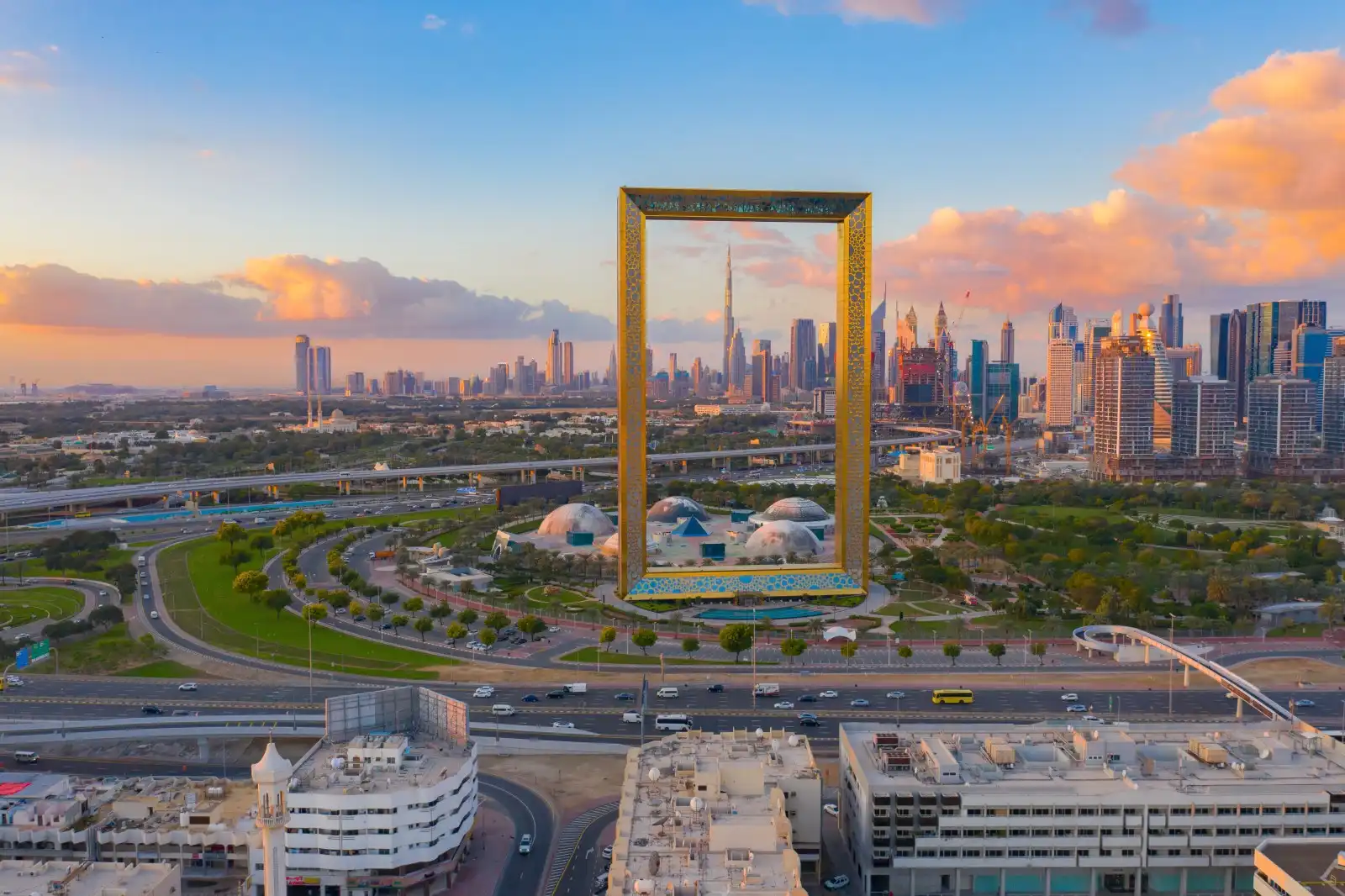 Aerial view of the golden Dubai Frame with Burj Khalifa and the Downtown Dubai skyline visible through its opening