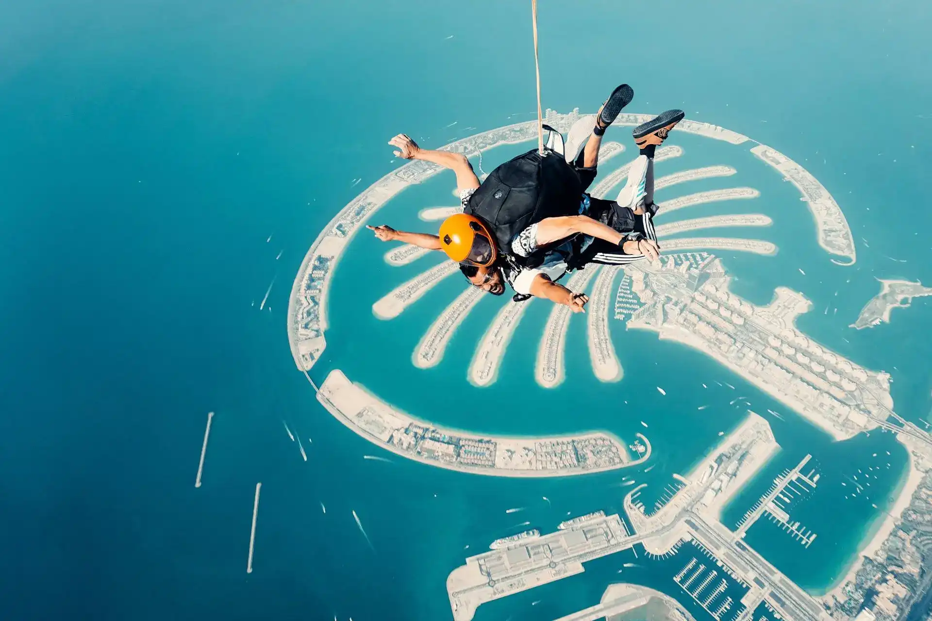 Tandem skydivers in free fall high above Palm Jumeirah's iconic palm-shaped island in Dubai