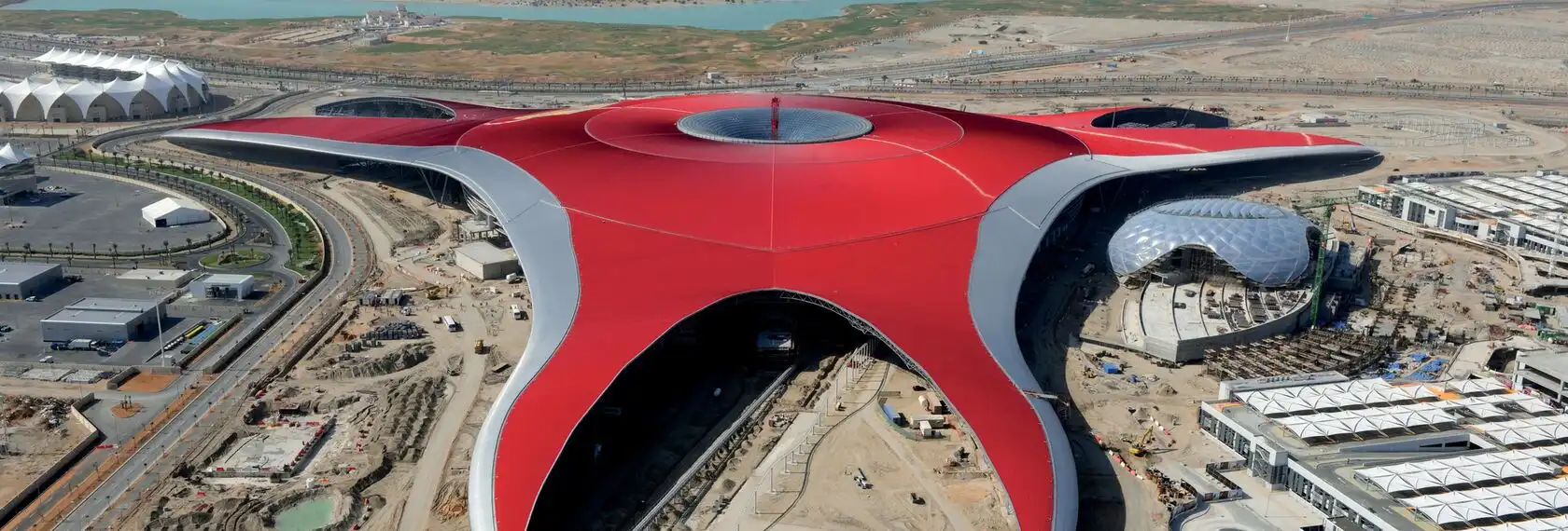 Close aerial view of Ferrari World's distinctive red roof structure with its central glass dome on Yas Island, Abu Dhabi