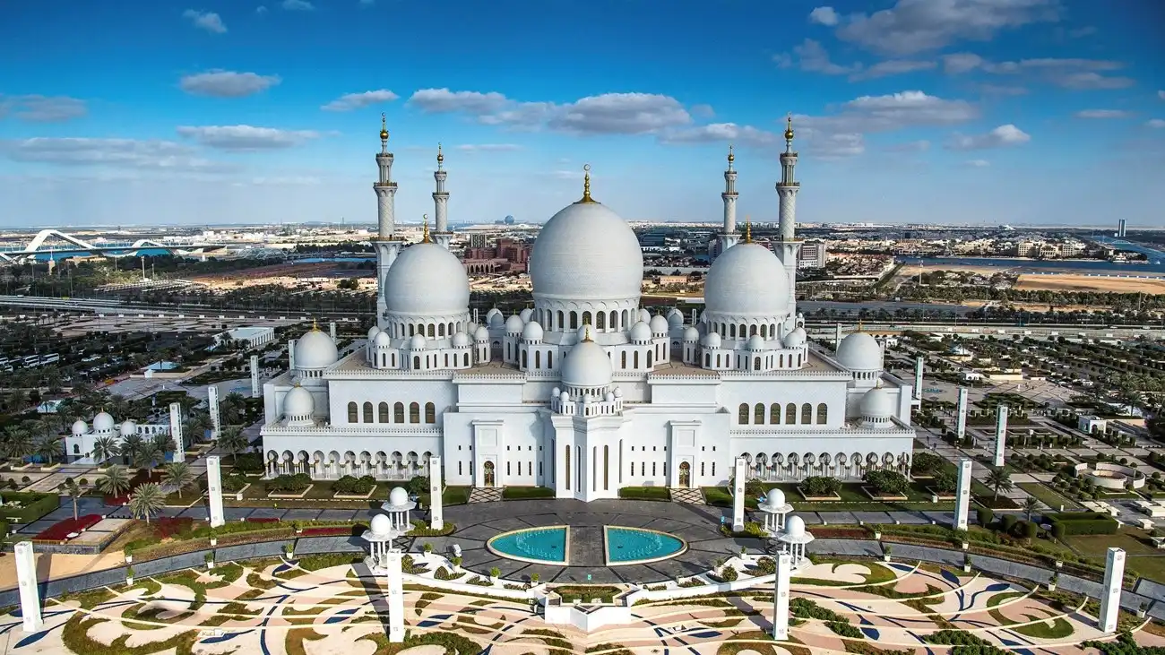 Aerial view of Sheikh Zayed Grand Mosque in Abu Dhabi showing its white marble domes, minarets, and reflecting pools